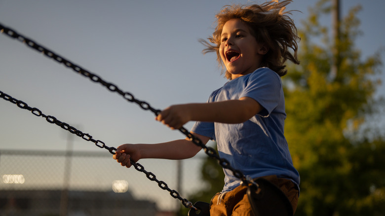 Child enjoying swings on playground