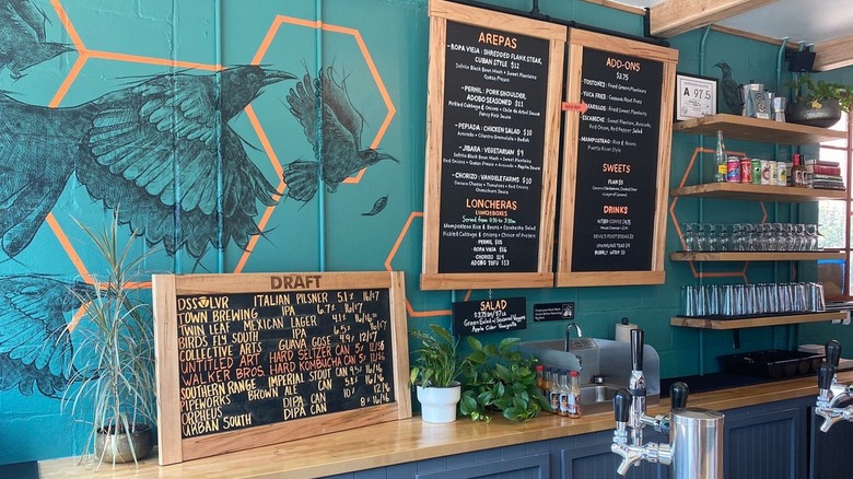 Menus, a painting of a crackle, and beer taps behind the bar at Asheville's Little Chango