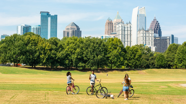 Four cyclists in Piedmont Park with view of Midtown Atlanta skyline in the distance