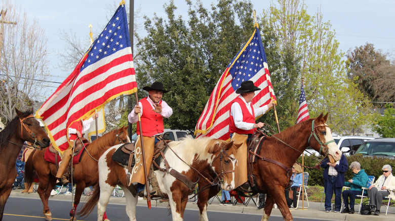 Horses carrying American flags walk in parade in Oakdale