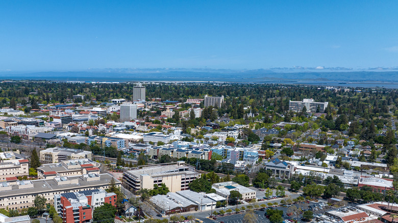 Aerial view of commercial and residential areas of Menlo Park, California, surrounded by lush greenery in distance