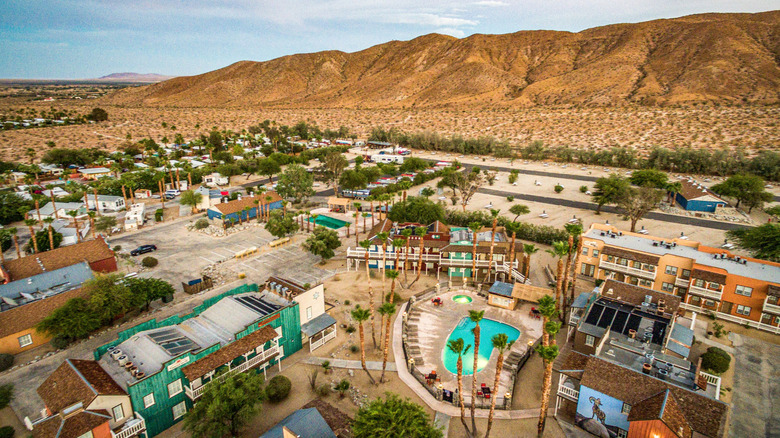 Aerial view of Borrego Springs, California, on a clear day showing houses, pools, mountains, palm trees, and desert terrain