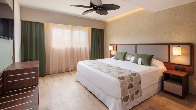hotel room showing bed with white sheets and green pillows