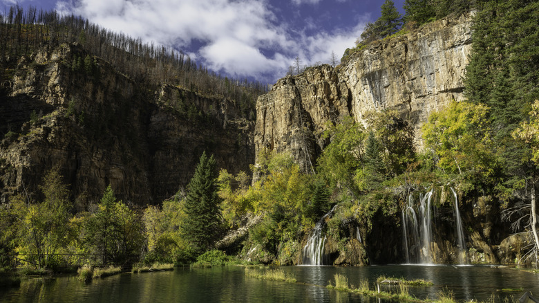 Rugged cliffs dotted with pines surrounding Hanging Lake, in Glenwood Canyon, Colorado.