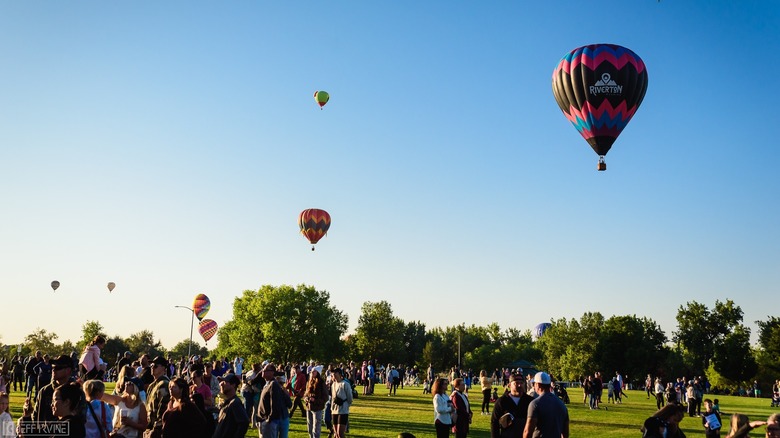 People enjoy Windsor's Harvest Festival while colorful hot air balloons fly in the background