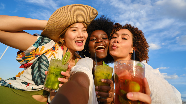 Three girls holding fruity cocktails