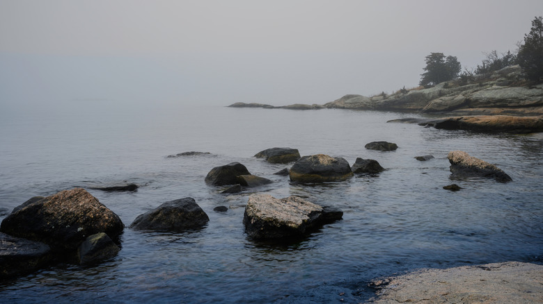 Foggy seascape with glacial stones, misty islands, and hilly cliffs at Rocky Neck Beach State Park, Connecticut