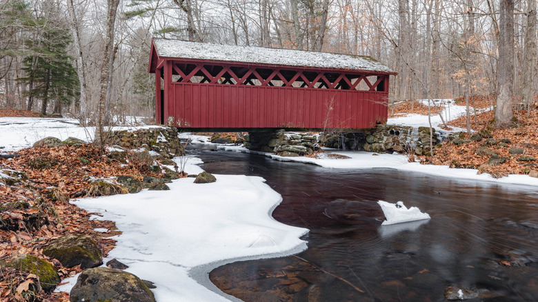 Covered red bridge over snowy river in Killingworth, Connecticut