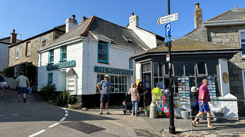 People standing in front of The Mousehole Gift Shop in Mousehole, Cornwall