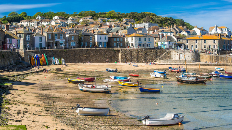 boats on the beach, with houses in the background, at the fishing village of Mousehole, Cornwall