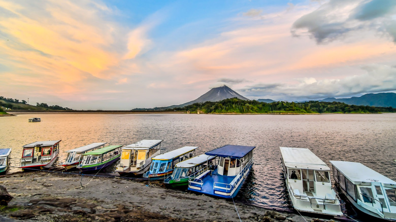 Boats line the shores of Lake Arenal with a volcano in the distance