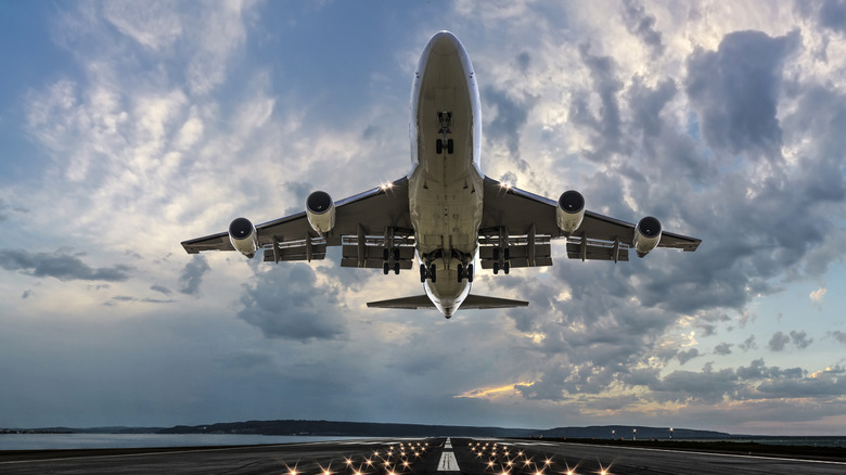 Plane taking off at airport, viewed from the runway below