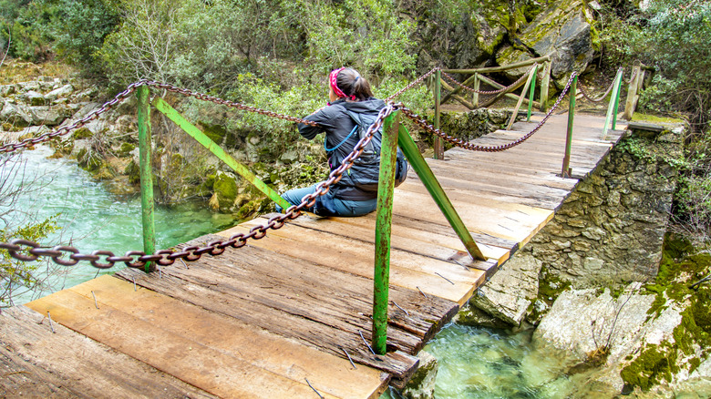 A girl sitting one a bridge at the Río Barosa, Spain