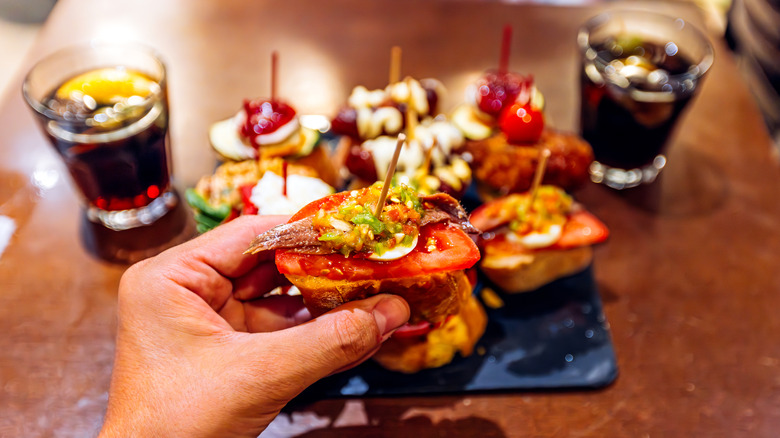 A person holding tapas in front of a plate