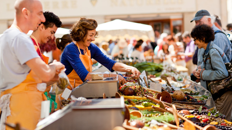 People smiling while selling and buying food at a festival in Europe
