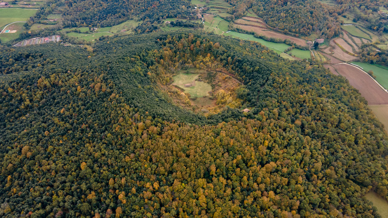 An aerial view looking down at a dormant volcanic crater with a church in the middle