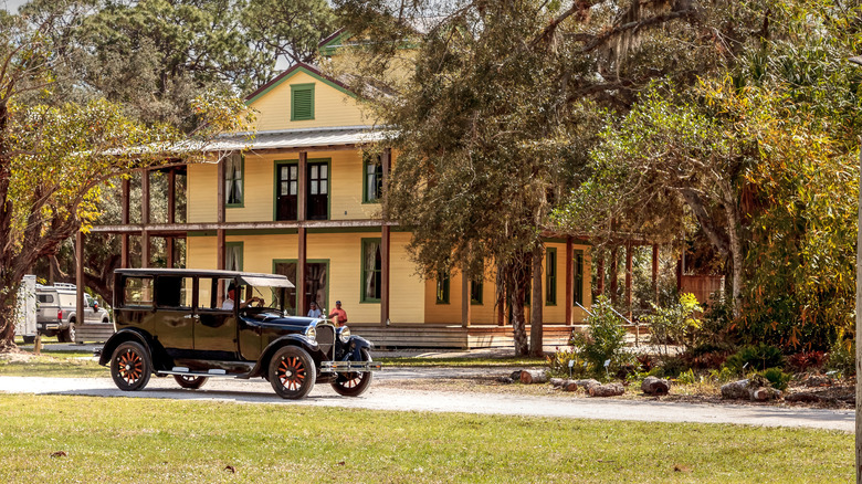 A vintage car in front of a historic house
