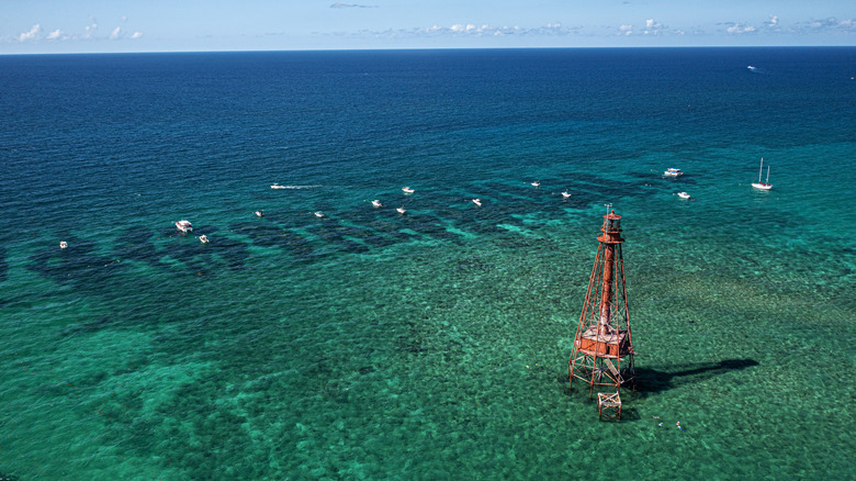 A lighthouse in the water with boats around it