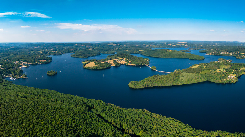 A drone view of Lac de Vassivi&egrave;re with deep blue waters, islands with trees, and the surrounding lush countryside