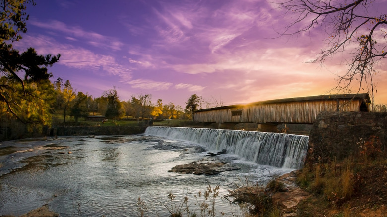 Dusk turns the sky purple above the bridge and dam overflow at Watson Mill Bridge State Park, in Georgia.
