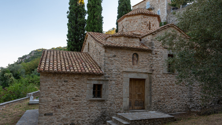Small stone church featuring a wooden door and multiple windows in Karytaina