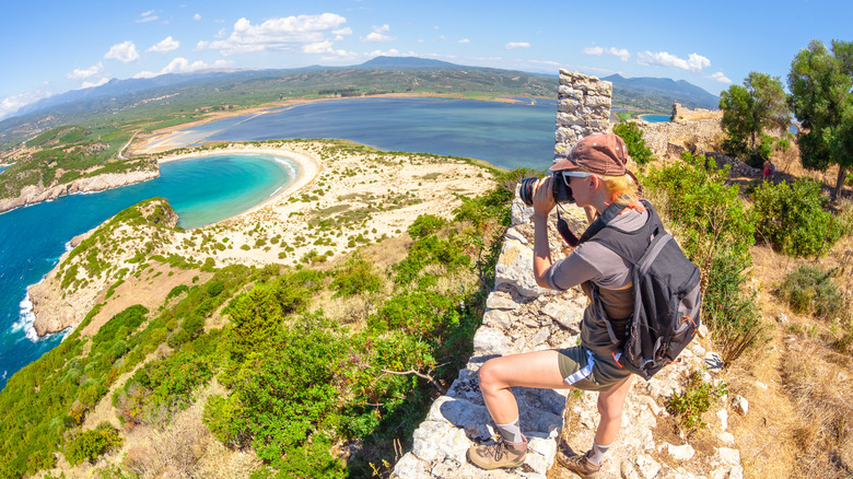 woman photographs Voidokilia Beach from Navarino Castle lookout