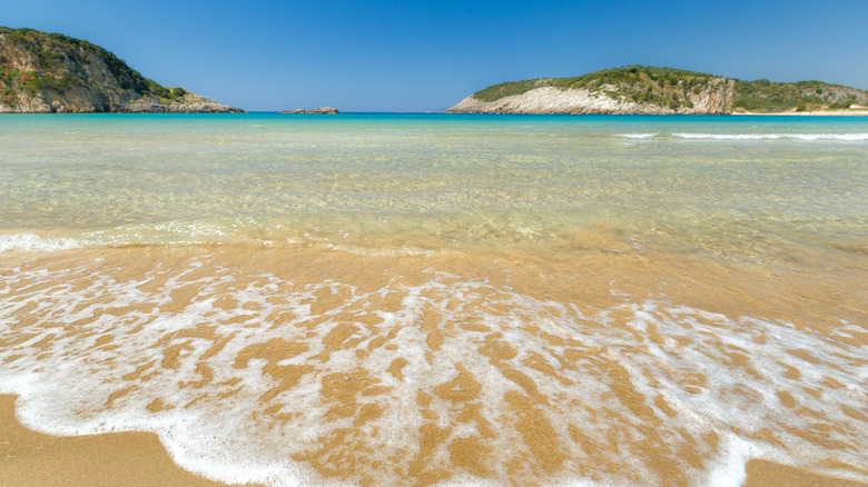 small waves crash the shore on a sunny day at Voidokilia beach