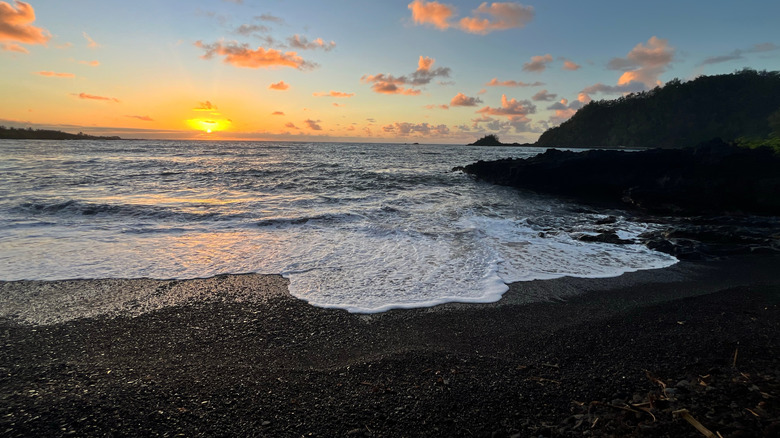 Orange sunset on black sand beach at Wai'ānapanapa State Park in Maui, Hawaii.