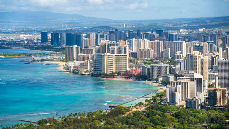 Aerial view of downtown Honolulu during the day with buildings, mountains, and the ocean in the background.