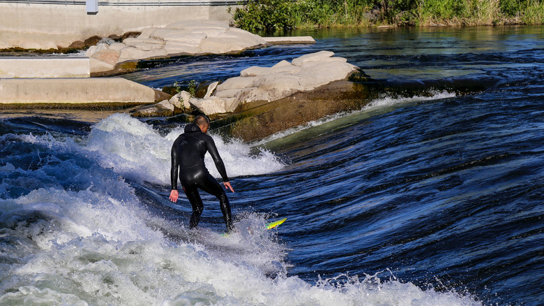 A man surfing on the Boise River at Boise Whitewater Park along the Boise River Greenbelt in Boise, Idaho