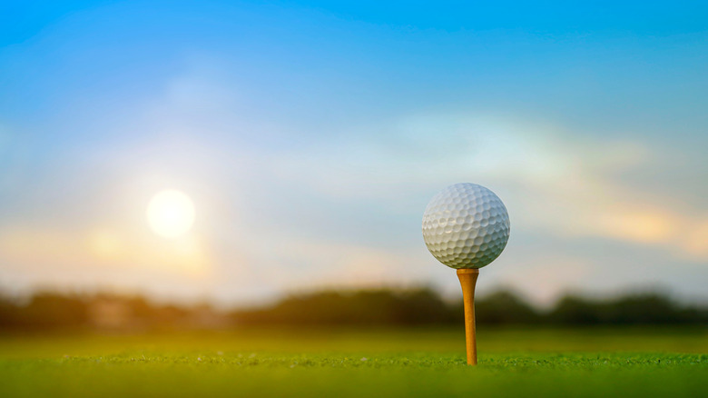 Golf ball on tee in front of sun rise