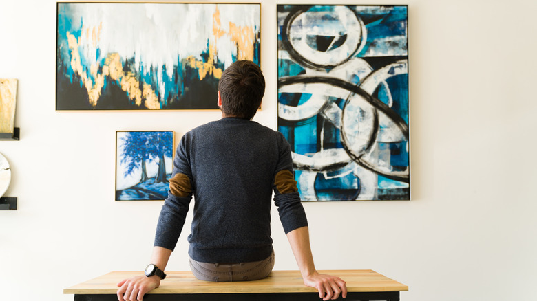 View of a man sitting on a bench and admiring art on the wall