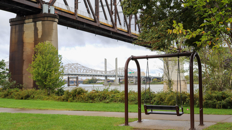 Park facing the Ohio river under a large bridge with another in the background.