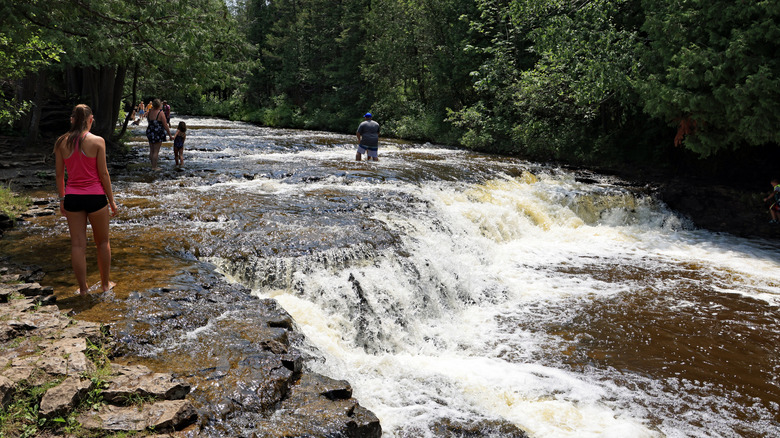 People swimming and walking along the small rapids at Ocqueoc Falls, Michigan