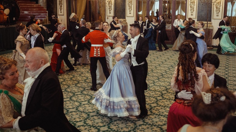 People in traditional clothes dancing in an ornate hall