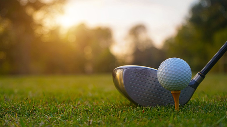 Golf club and ball at sunset