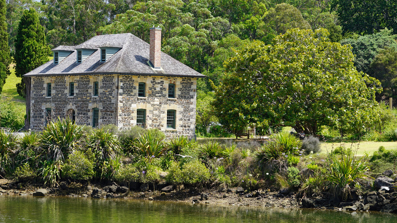 The historic Stone Store in Kerikeri surrounded by green trees and next to the water