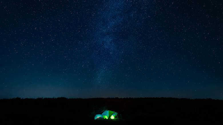 Tent lit up against Milky Way and trees North Carolina