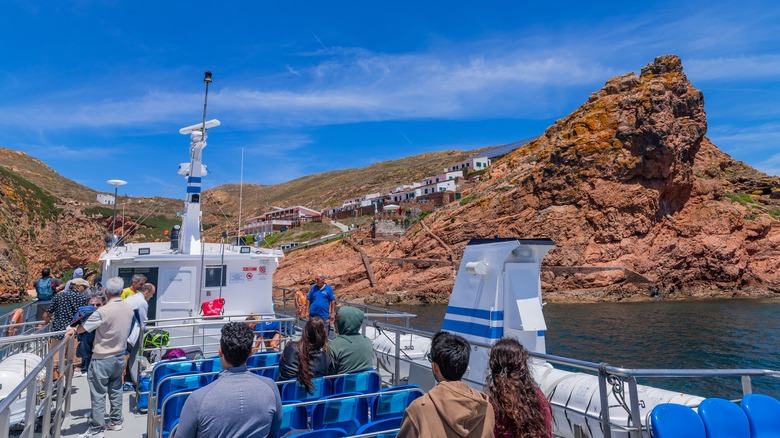 Peple watching from deck of ferry as it approaches rugged coast