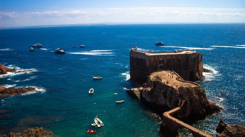 Ancient stone fort on island in sea with boats in the water