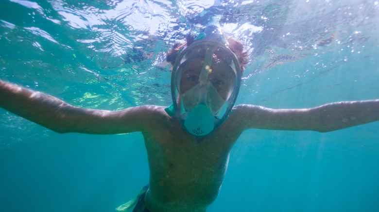 A teenage boy with a snorkel mask on in the water in Portugal.