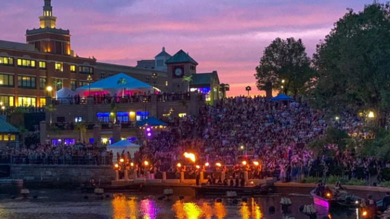 A lighting of WaterFire at sunset in the Waterplace basin in downtown Providence, Rhode Island. In the background is the Providence Place shopping mall.