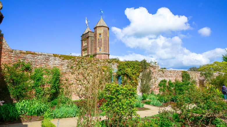 Flowerbeds and a vine-covered wall in front of the tower of Sissinghurst Castle, England