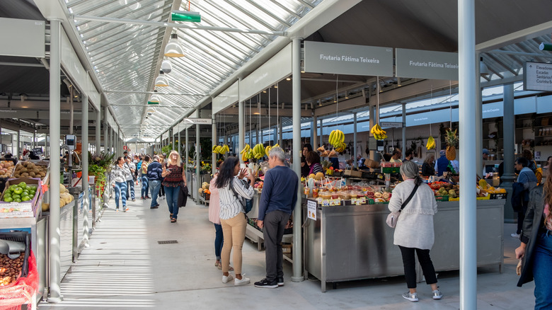 Shoppers look at produce in the modern interior of Bolhão Market in Porto, Portugal