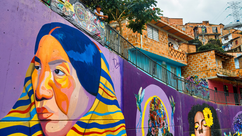 Colorful mural featuring two women's faces beneath red brick houses in Comuna 13