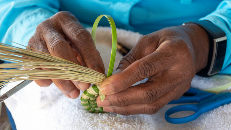 A woman weaving a sweetgrass basket.