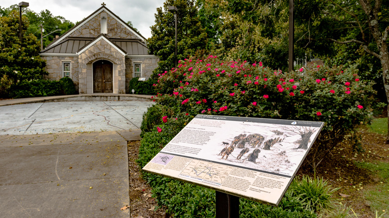 Trail of Tears Interpretive Center with an informational sign in the foreground and small stone building in the background.