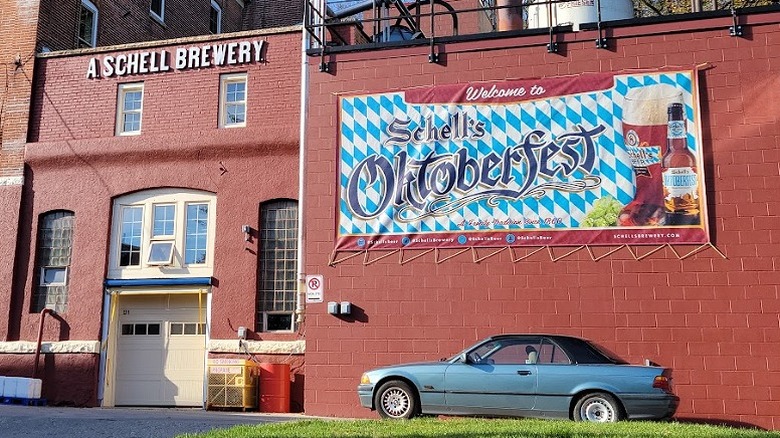 Outside the red-brick front of August Schell Brewing with an Oktoberfest banner on the wall