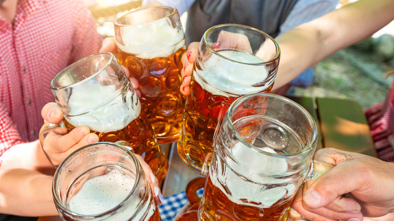 People cheering with five steins full of beer during Oktoberfest celebrations