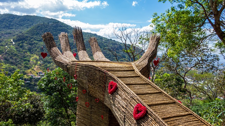 Mano Del Mantra hand extends into lush jungle and mountains